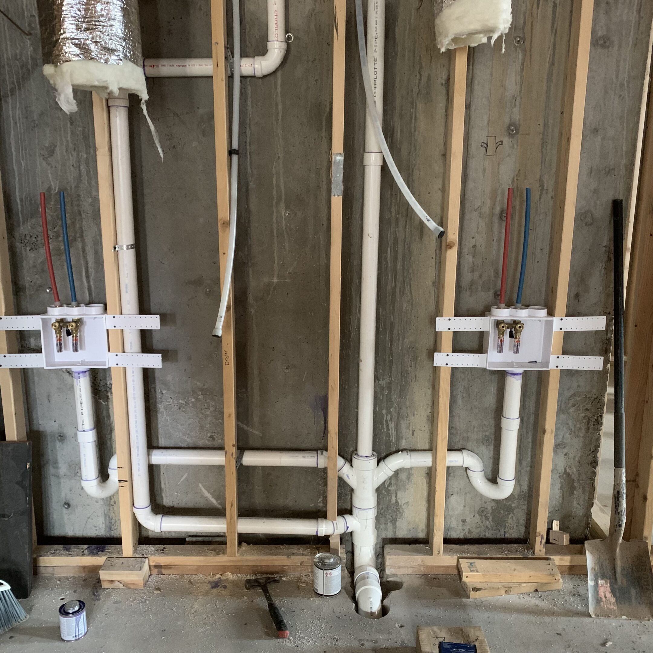 Exposed plumbing pipes and valves in a wall under construction.