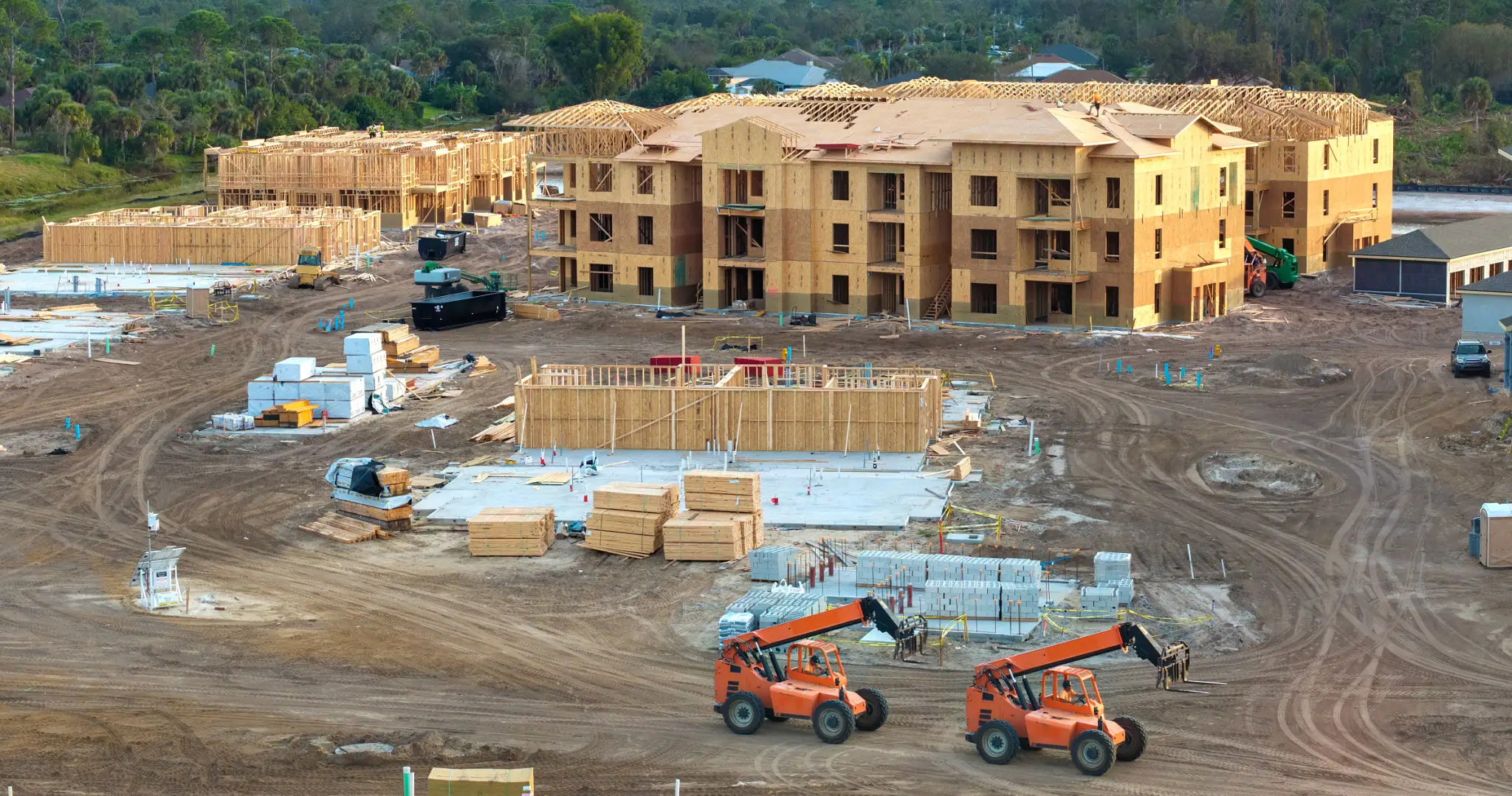 Construction site with multiple buildings and heavy machinery.