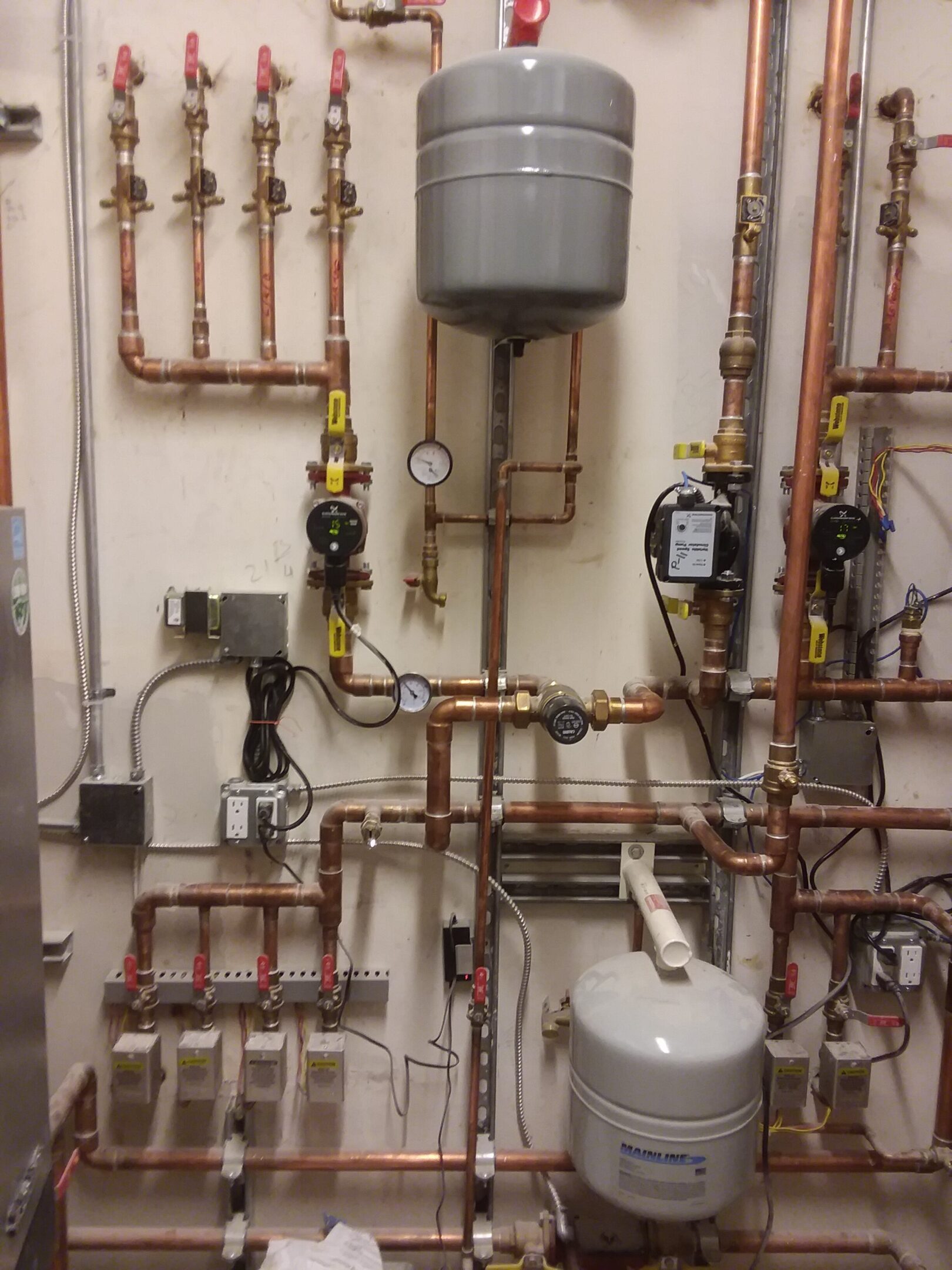 Complex plumbing system with multiple copper pipes and gauges.