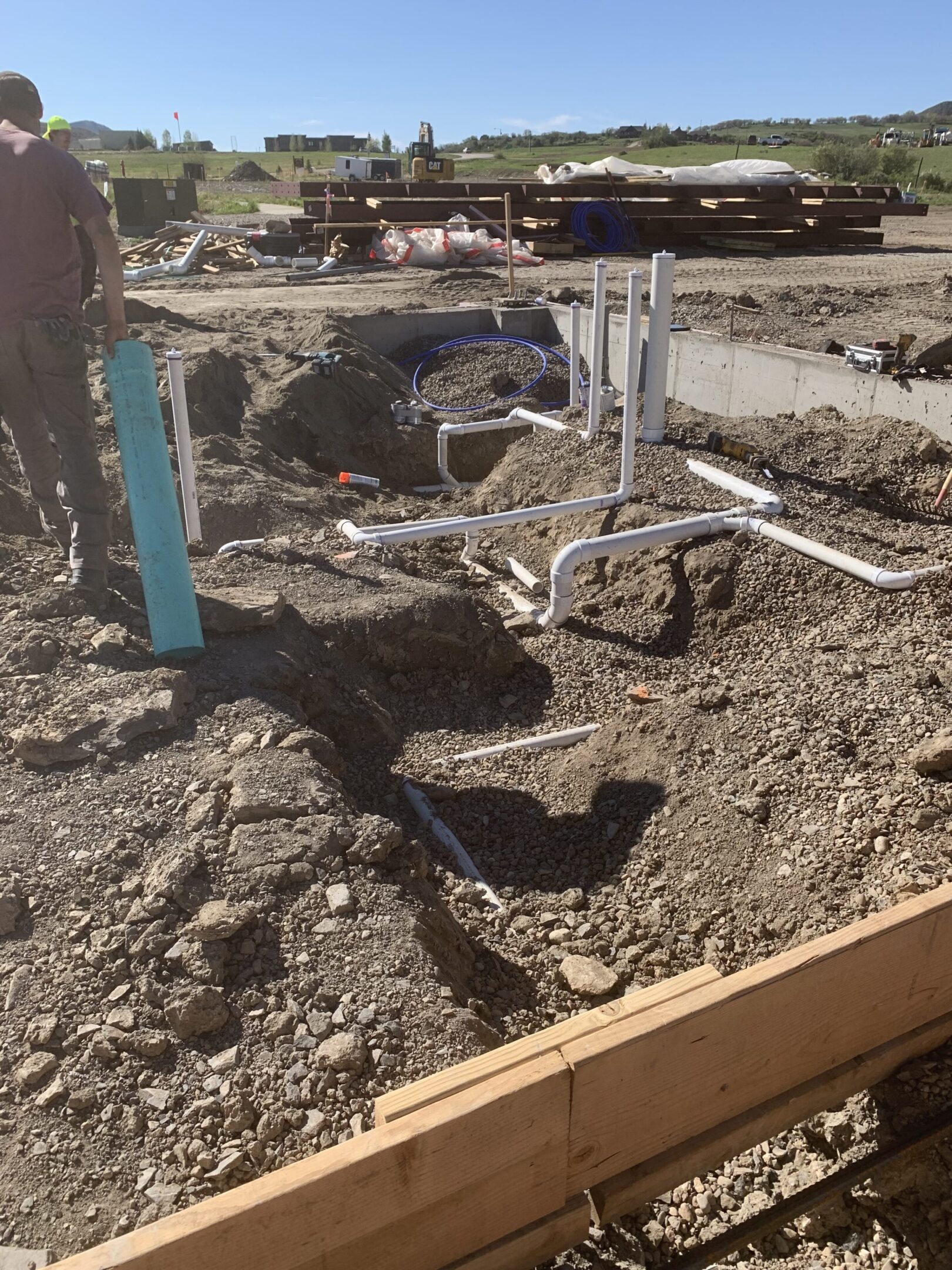 Excavated ground with visible pipes and a valve for plumbing installation.