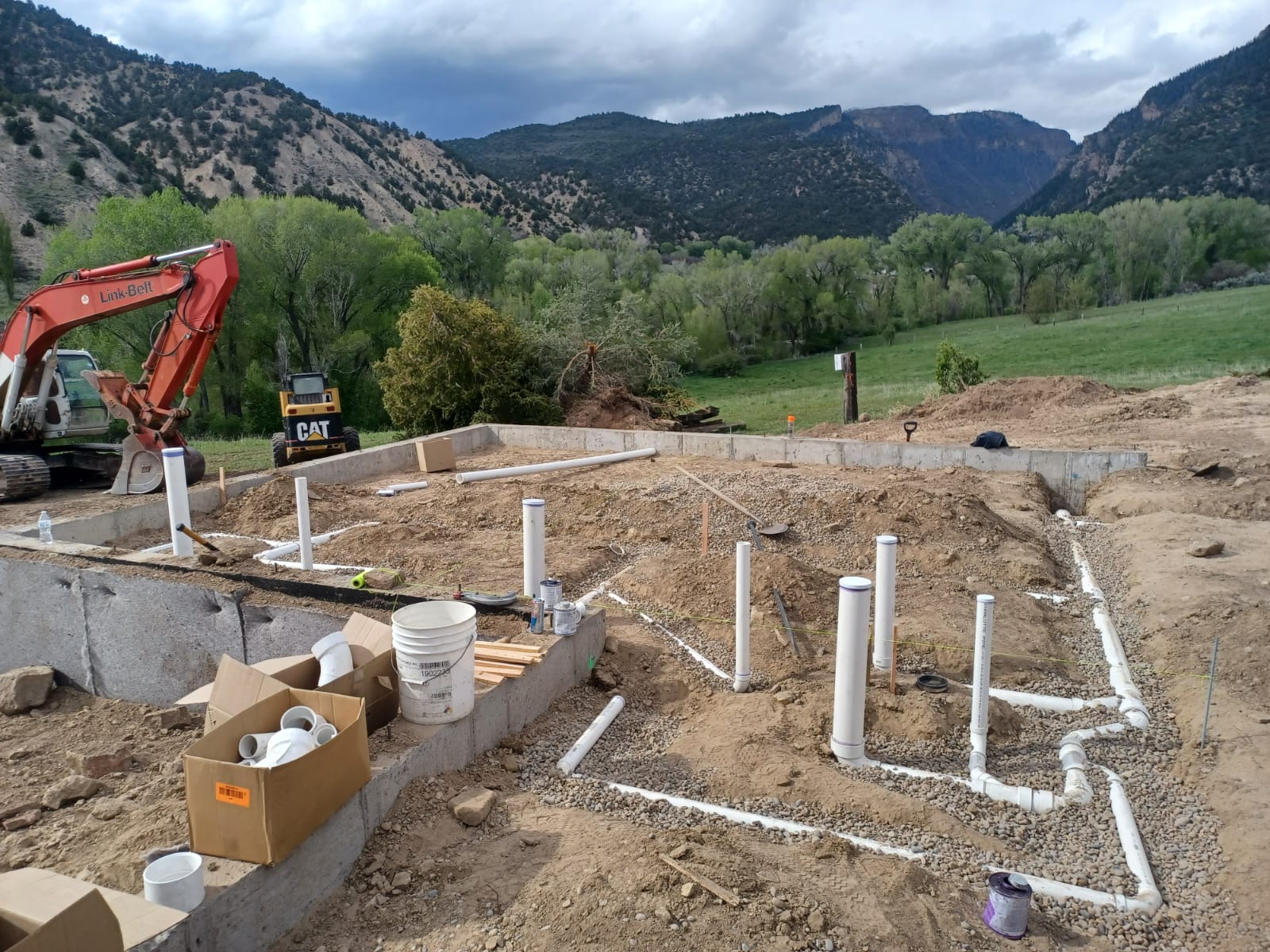 Construction site with plumbing pipes laid out on a foundation.