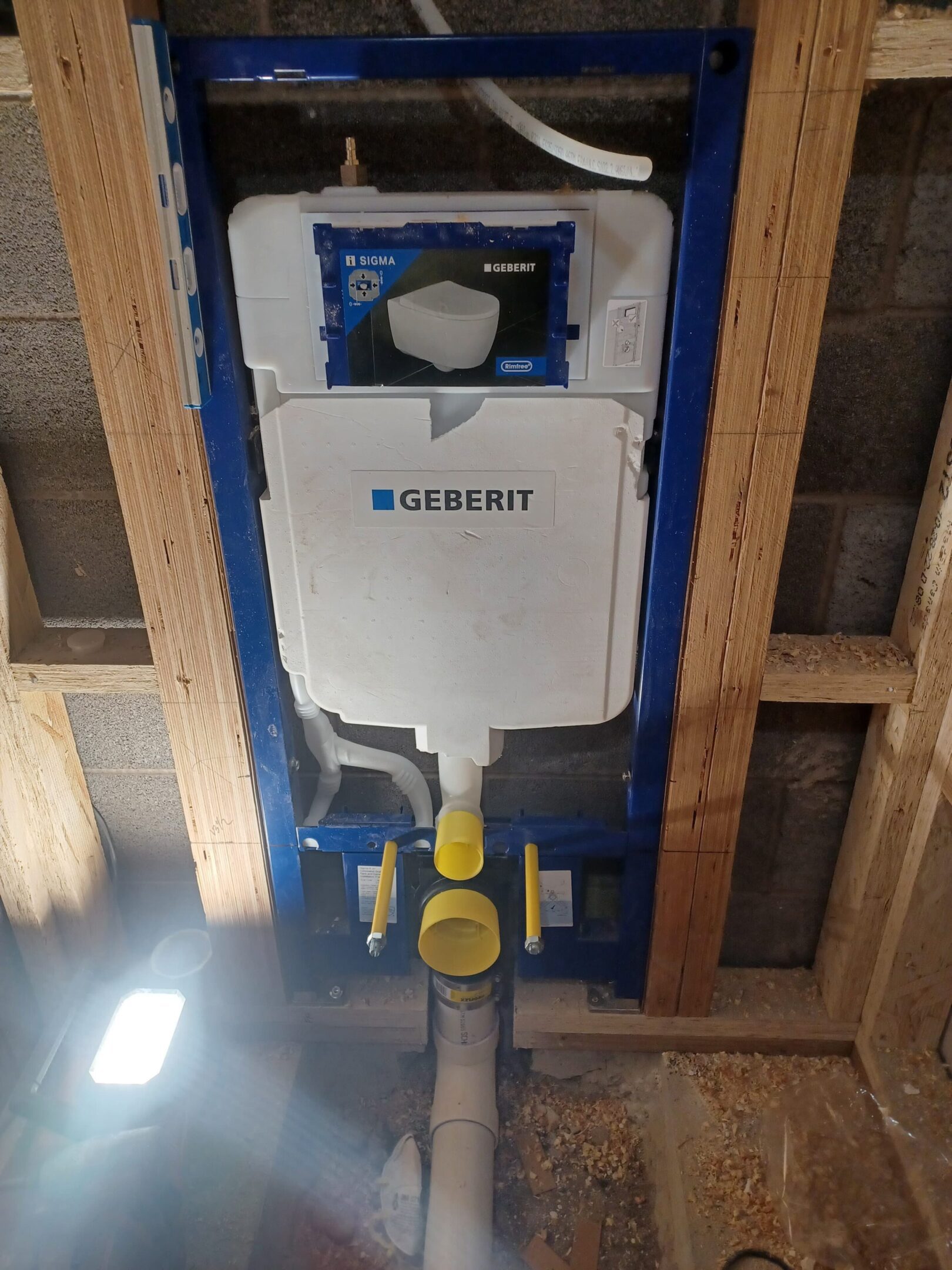 Installed Geberit concealed toilet tank in a wooden frame structure.